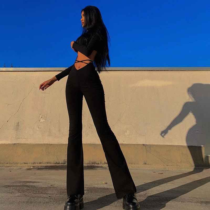 Stylish woman wearing flared track pants with high comfort paired with a trendy top against a blue sky