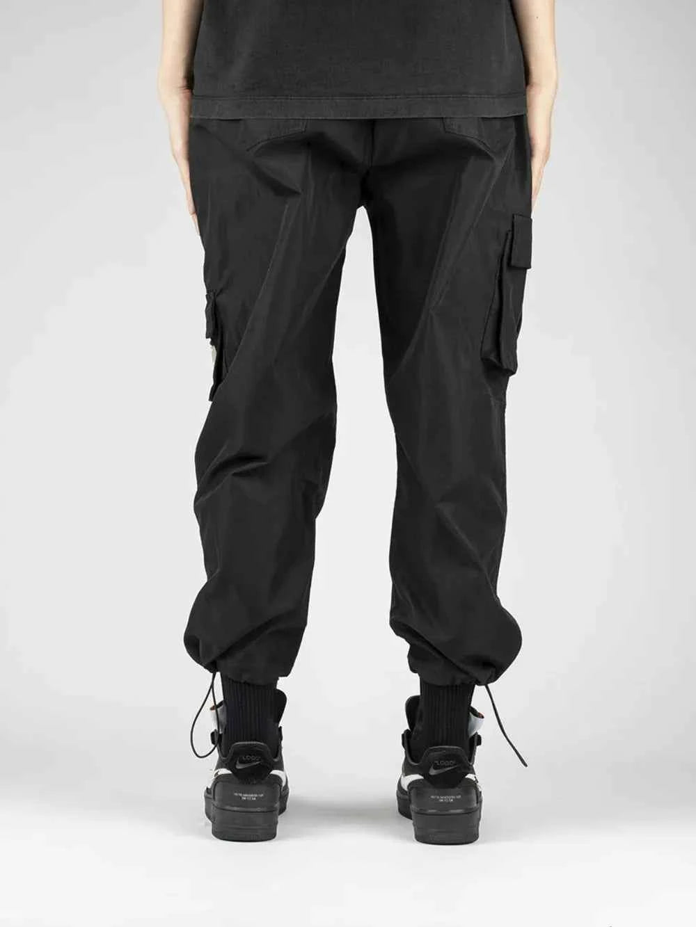 Back view of men's drawstring cargo pants in black with multiple pockets and cuffed hems