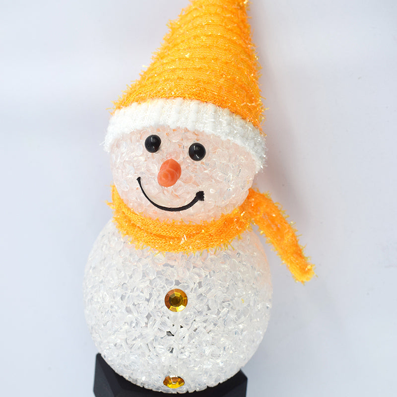 Solar snowman garden lamp with a cheerful expression and bright orange scarf for festive outdoor decoration