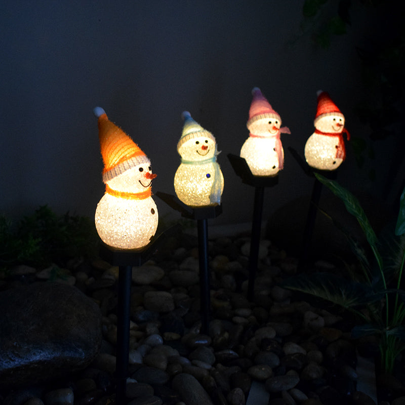 Decorative solar snowman garden lamp set glowing softly in a garden at night