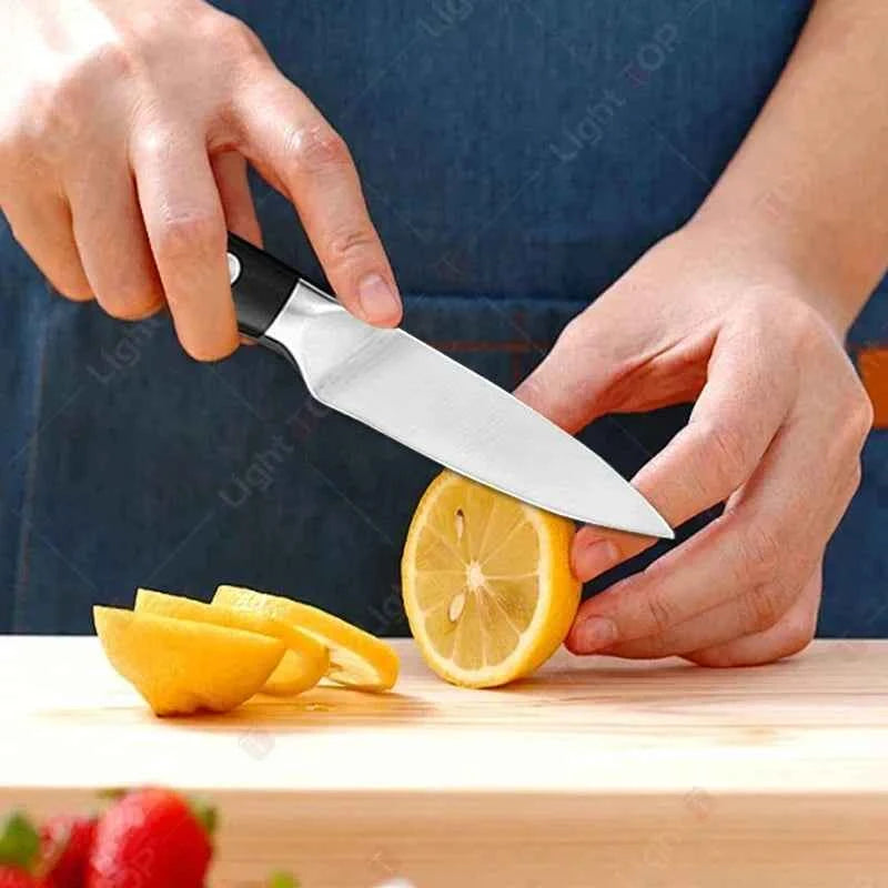 Person using a stainless steel paring knife to slice fresh lemon on a wooden cutting board