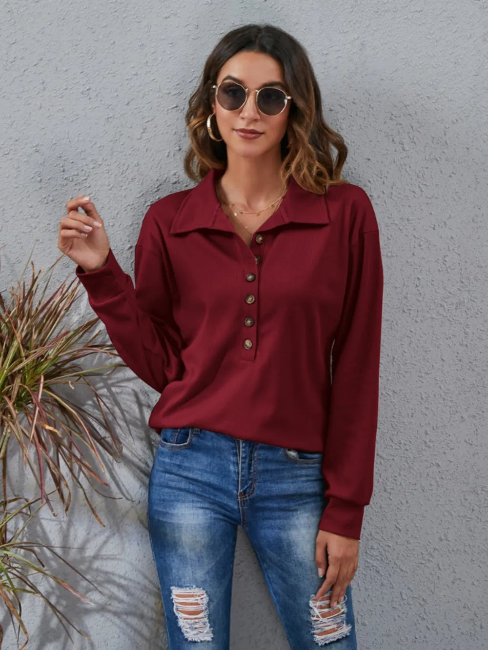 Stylish model wearing a women's classic blouse in burgundy with button details and long sleeves